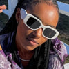 Eine schwarze Frau trägt die weiße  Anozetti Sonnenbrille